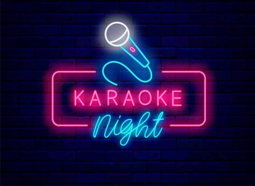 Colorful neon sign for Karaoke Night with a microphone, set against a dark brick wall background. Perfect for party fun!